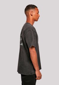 Gray oversized t-shirt made of cotton, featuring short sleeves, a crew neck, and a graphic print on the back. Simple design, relaxed fit.