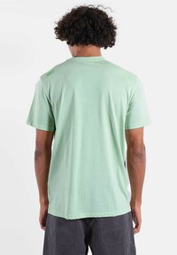 T-shirt vert menthe à manches courtes, col rond, tissu doux, avec un logo discret sur l'épaule gauche.