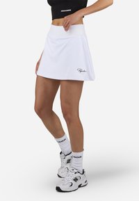 Valge sportlik seelik laia puusavööga, laienev disain ja tikandiga logo. Kombineeritud valgete tossudega ja mustriga sokkidega.
