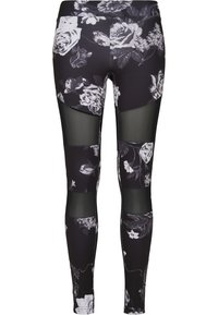 Svarta träningsleggings med vitt blommönster, med transparenta meshnätpaneler och en figurnära design. Mjuk tyg med slät textur.