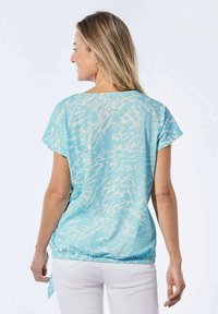 Lichtblauw top met een getextureerd golfpatroon, korte mouwen en een cinched zoom. De stof lijkt zacht en lichtgewicht.