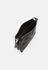 Czarna skórzana torba z tłoczonym wzorem, wyposażona w dwie zamykane na zamek komory oraz srebrne okucia. Gładka faktura, przemyślany, strukturalny kształt.