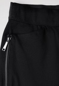 Black fabric with a smooth texture features a waist band and a side zip pocket with silver hardware.