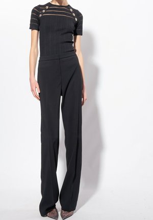 Black ribbed knit top with sheer stripes, featuring gold buttons; paired with black, wide-leg trousers and textured pointed-toe heels.