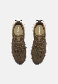 Olivgröna mesh-sneakers med en texturerad överdel, som har platta skosnören och en vit mellansula med svarta detaljer. Timberland-logotyp på tungan.
