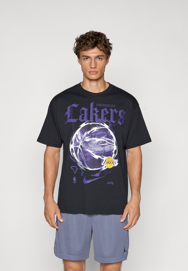 Sort oversized t-shirt med lilla "Lakers" tekst, et basketballgrafik og Nike-logo. Bæres med lysegrå perforerede shorts.