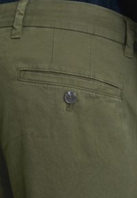 Spodnie bawełniane w kolorze oliwkowej zieleni z tylną kieszenią, zapinane na guzik o gładkiej fakturze. Widoczne subtelne detale przeszyć.