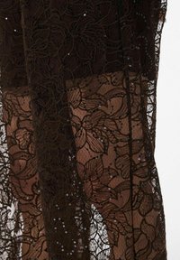 Black lace fabric with floral pattern and sequins, semi-transparent texture, showcasing intricate detailing and flowing design.