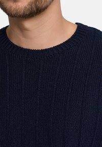 Marinetrui van gebreid materiaal met een geribbelde textuur en een klassieke ronde hals. De stof heeft een iets chunky uitstraling met verticale lijnen.
