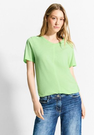 T-shirt verde chiaro a maniche corte con scollatura rotonda, tessuto morbido e vestibilità rilassata, abbinato a jeans di denim blu.