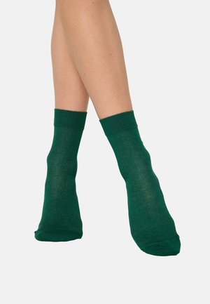 Grüne Knöchelsocken mit einer weichen, glatten Textur und gerippten Bündchen, die sich eng um die Knöchel schmiegen.
