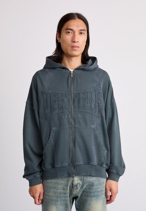 Donkerblauwe rits hoodie met een voorzak en geborduurde tekst "VERTERE BERLIN". Heeft een relaxte pasvorm en een zachte stoftextuur.