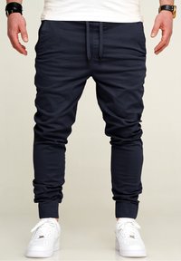 Marine Jogginghosen aus weichem Baumwollmix, mit elastischen Bündchen und Kordelzug an der Taille. Kombiniert mit weißen Sneakers für einen Kontrast.