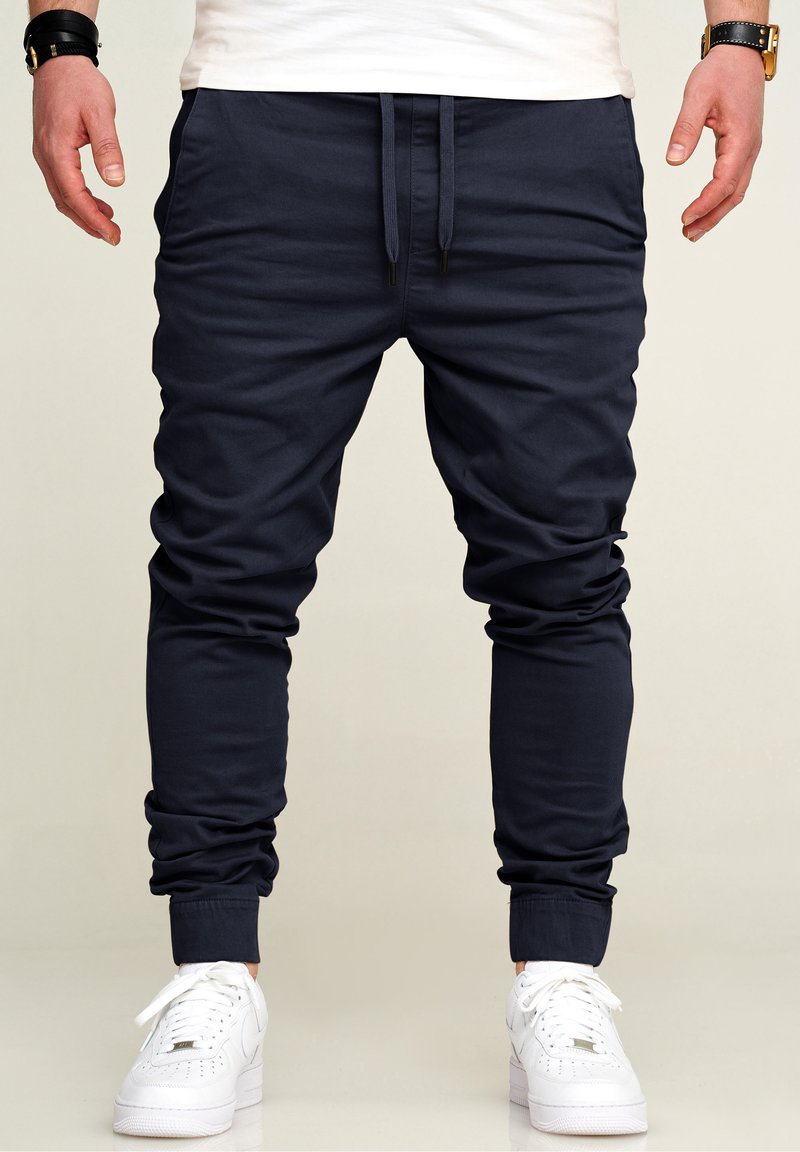 Marine Jogginghosen aus weichem Baumwollmix, mit elastischen Bündchen und Kordelzug an der Taille. Kombiniert mit weißen Sneakers für einen Kontrast.