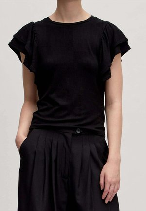 Schwarzes, geripptes T-Shirt mit kurzen, gerafften Ärmeln, rundem Ausschnitt und taillierter Silhouette, kombiniert mit hoch taillierten schwarzen Hosen.