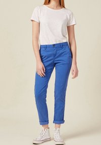 Blå chinos med slim fit, uppvikta fållar, i bomullsmaterial, framfickor och en enkel knappstängning, kombinerade med en vit T-shirt med rund halsringning.