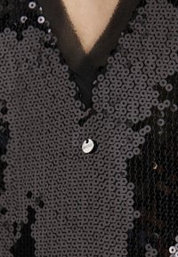 Fekete flitteres felső V-nyakú kialakítással, kör alakú flitterekből készült, fényes felülettel. Az ezüst címke "BOSS" felirattal van ellátva.