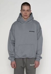 Šedá mikina s kapucňou, predným vreckom a rebrovanými manžetami. Na hrudi čierne logo "MULTIPLY". Mäkká textúra a pohodlný strih.
