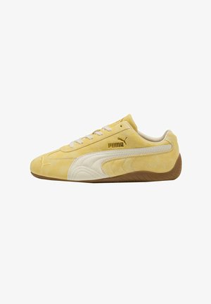 Baskets Puma en daim jaune avec une bande latérale blanche, une semelle marron et des lacets blancs, vues de profil en direction de la gauche.
