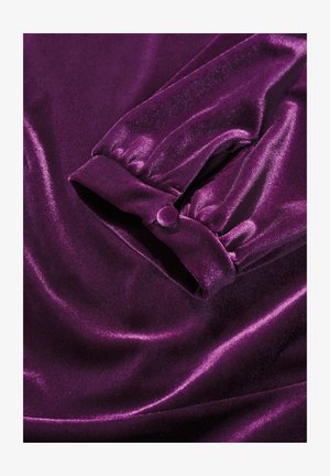 Purple velvet fabric with a smooth, shiny texture. Features a gathered cuff with a button detail. Overall soft and luxurious appearance.