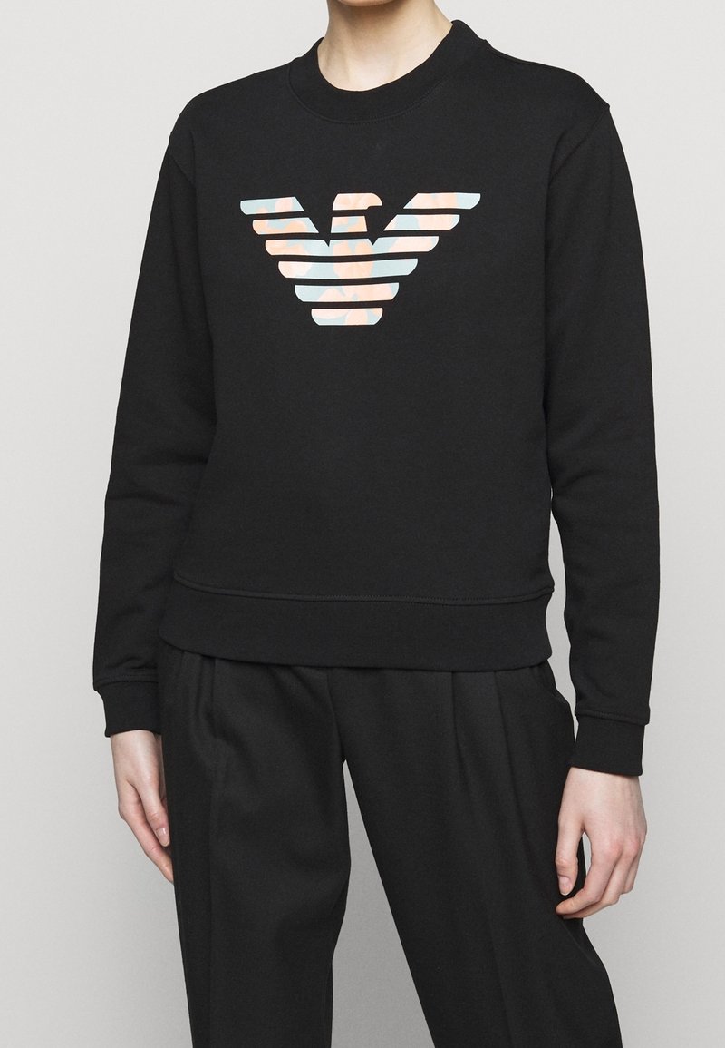 Felpa nera con collo tondo e logo a strisce colorate sul davanti. Tessuto morbido, con polsini e orlo a coste.