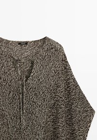 Maglione in maglia mélange marrone e bianco con scollo a V e chiusura frontale con laccetto, mostrato disteso su uno sfondo bianco.