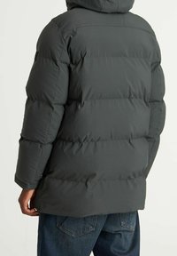 Chaqueta con capucha aislante de color gris oscuro, con un diseño acolchado, costuras visibles y mangas largas. La parte posterior muestra una textura suave y hardware mínimo.