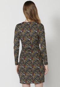 Sukienka z długim rękawem w czarnym kolorze, zdobiona kwiecistym wzorem z żółtymi, czerwonymi i białymi akcentami. Dopasowany krój z wcięciem w talii.