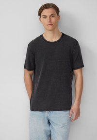 Zwarte katoenen t-shirt met een ronde halslijn en korte mouwen, met een gestructureerde afwerking. Draagt het met lichtblauwe denim shorts.