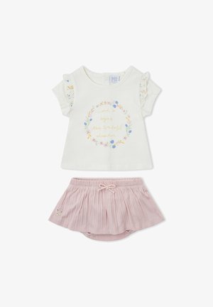 Camiseta blanca para bebé con mangas de volantes florales y texto dorado, combinada con bombachos rosa plisados con parche en forma de corazón.