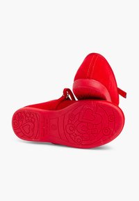 Zapatos de ante rojo con punta redondeada y un tacón bajo. Suela de goma texturizada con patrones florales y de corazones. Detalles de correa en la parte posterior.