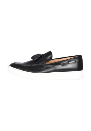 Mocassino slip-on in pelle nera con nappine e suola spessa in gomma bianca, mostrato di profilo su sfondo bianco.