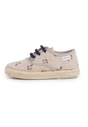 Chaussure enfant en toile beige avec ancres bleu marine imprimées, lacets bleu marine, semelle tissée et petite étiquette de marque colorée sur le côté.
