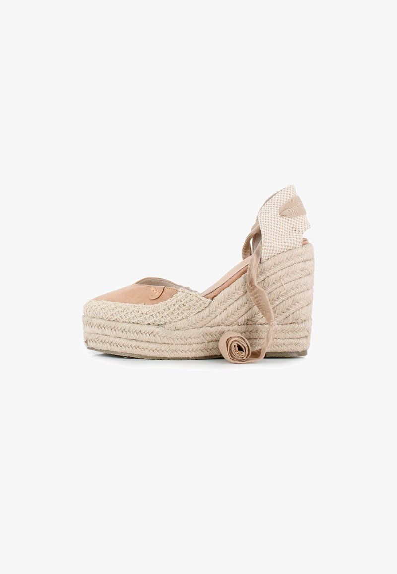 Cuña de espadrille beige con suela de yute trenzado, tira de tela en el tobillo y punta redondeada. Parte superior de ante suave con detalle estampado cerca del talón.