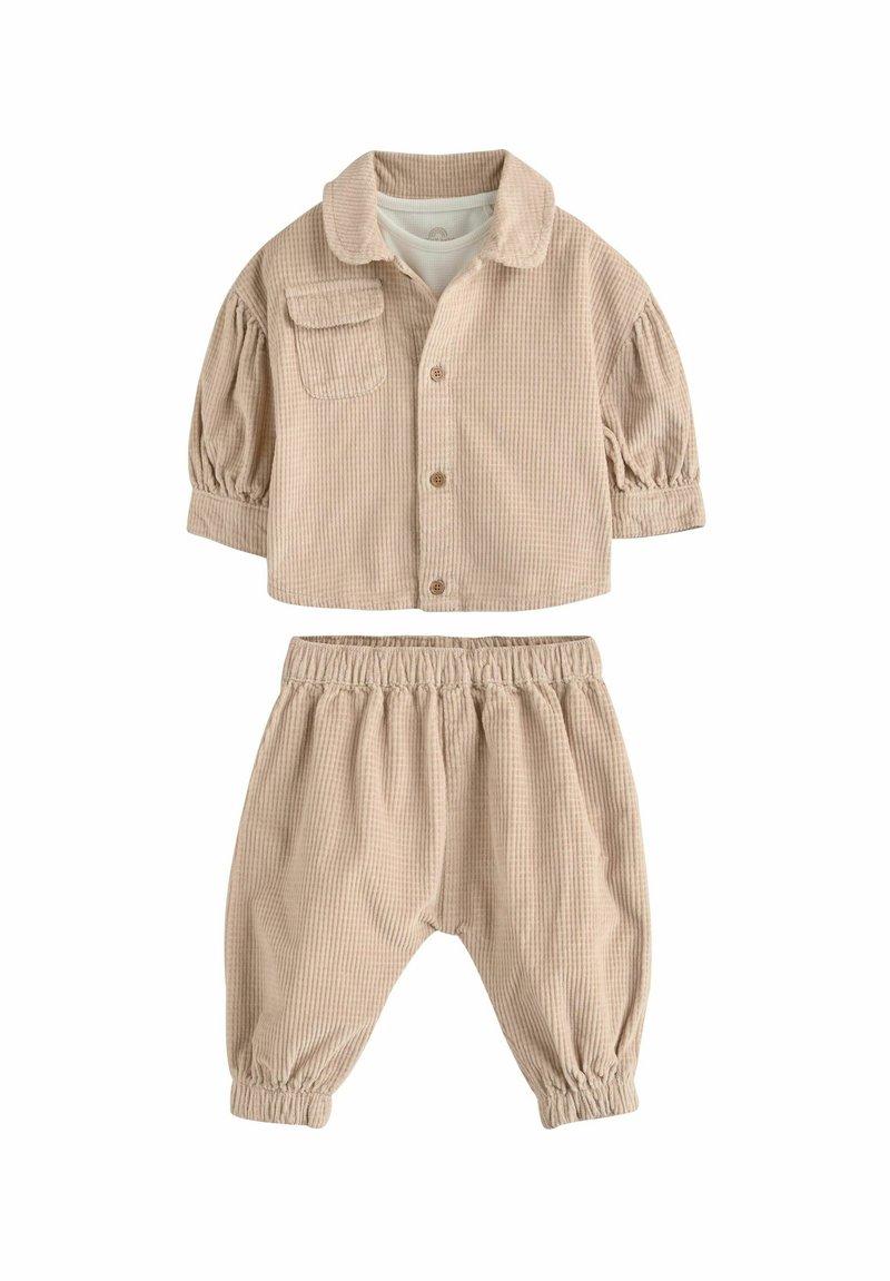 Beige kordbársony kétszínű szett, amely egy galléros gombos zakóból áll, zsebbel és rugalmas derekú nadrágból összegyűrt szegéllyel.