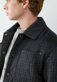 Wollen gemengde button-up jack in een donker geblokt patroon, met een klassieke kraag, borstzak en drukknoopsluitingen met een gestructureerde afwerking.