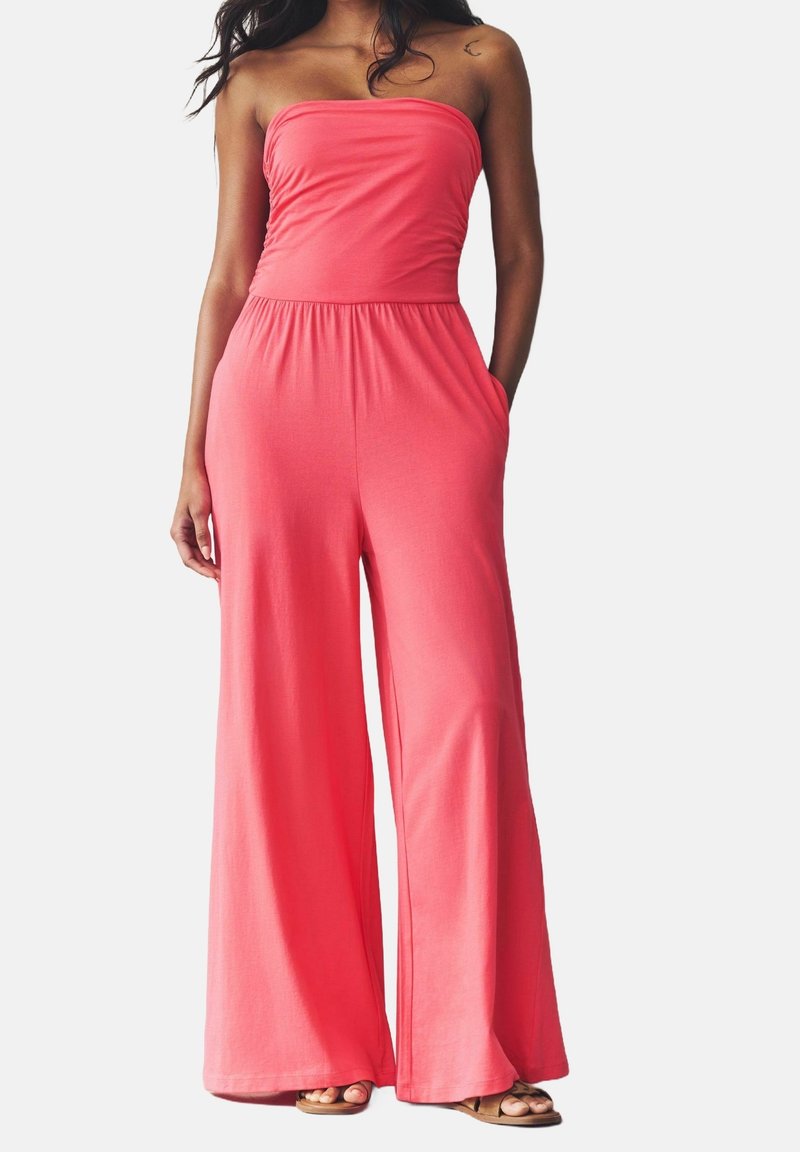 Koralfarvet strapless jumpsuit med brede ben, elastisk talje og sidelommer, lavet af blødt stof, der tilbyder en afslappet pasform og glat tekstur.