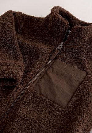 Brown fleece jacket with a high collar, featuring a zippered front and a patch pocket in a smooth, darker brown fabric. Soft texture.