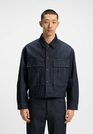 Donker denim jack met een verkort ontwerp, twee voorzakken en gebogen knopen. Voorzien van een klassieke kraag en een gestructureerde stof.