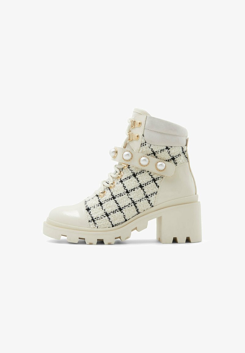Chunky-heeled ankle boot in cream faux leather and black-and-white checkered textile, featuring decorative straps with pearl accents.