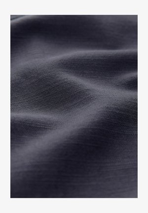 Temno sivo blago z gladko, rahlo teksturirano površino, ki ima subtilne gube in variacije svetlobe po materialu.