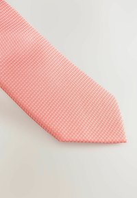 Strukturert slips i lyserød med et subtilt geometrisk mønster. Har en spiss tupp og glat overflade. Egnet til formelt tøj.