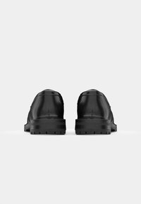 Black leather shoes with a smooth texture, rounded toe, and low rubber sole featuring a patterned tread design.