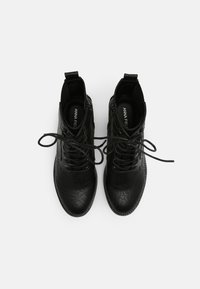Black ankle boots featuring textured leather, round toe, lace-up design, and pull tab at the heel for easy wearing.