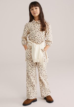 Loungewear set met luipaardprint, bestaande uit een blouse met kraag en knopen en een broek met wijde pijpen, uitgevoerd in beige met bruine en paarse accenten.