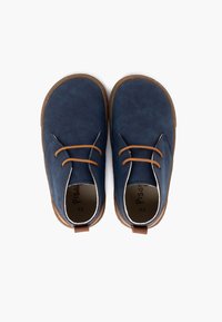 Scarpe per bambini di colore blu navy con tomaia texturizzata, lacci marroni e suola di gomma beige. Include un anello sul retro per indossarle facilmente.