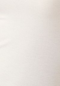 Tessuto beige a costine con una finitura liscia. Il materiale appare elastico e resistente, presenta un colore solido e neutro.