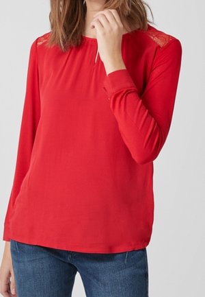 Rotes Langarmoberteil mit Spitzenakzenten an den Schultern, rundem Halsausschnitt und lässiger Passform, kombiniert mit blauen Jeans.