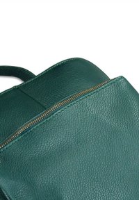 Sac à dos en cuir texturé vert foncé avec une fermeture éclair dorée et une petite poignée en haut.