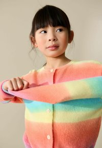 Cárdigan a rayas multicolor con textura suave, que presenta tonos de rosa, naranja, amarillo y turquesa, con cierre de botones en la parte delantera.